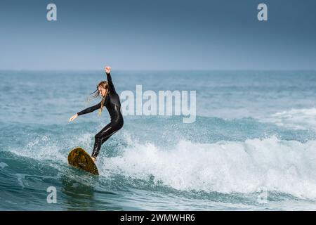 Ein Younhg Surfer, der im Fistral in Newquay in Cornwall in Großbritannien eine Welle reitet. Stockfoto