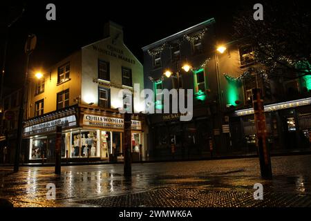 Niedriger Blick auf die Killarney High Street in der Nacht im Winter nach dem Regen im County Kerry Irland. Nächtlicher Blick auf die kleine Stadt Stockfoto