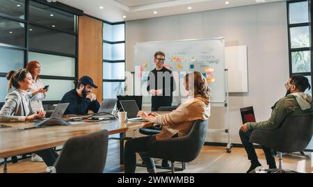 Experten aus verschiedenen Gruppen arbeiten in einem Konferenzraum zusammen und nehmen an einem lebhaften Brainstorming Teil. Sie diskutieren Ideen, zeigen Teamarbeit und c Stockfoto