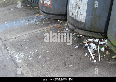 Abfallüberlauf außerhalb einer kommunalen Abfallfläche mit Recycling- und Mülltonnen über dem Zement mit Kopierraum. Konzept schmutziger urbaner Räume Stockfoto