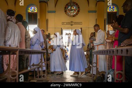 Katholische Nonnen und Seminaristen singen, während sie die St. Joseph's Cathedral zur katholischen Sonntagsmesse in Stone Town, Sansibar, Tansania betreten. Stockfoto