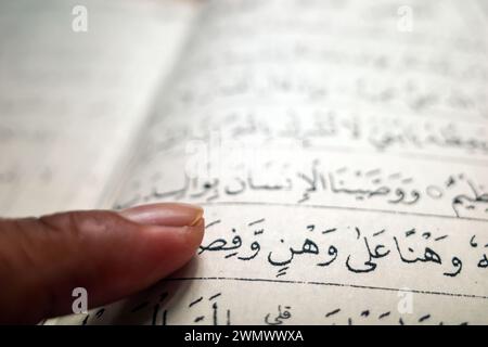 Ein Mann, der mit den Fingerzeigen auf die Worte auf Arabisch im Koran zeigt. Lernkonzept. Stockfoto