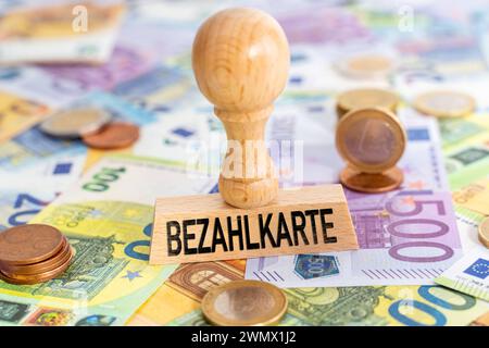 Augsburg, Bayern, Deutschland - 28. Februar 2024: Zahlungskarte für Flüchtlinge und Asylbewerber, Schriftzug auf einem Stempel auf Euro-Banknoten. FOTOMONTAGE *** Bezahlkarte für Flüchtlinge und Asylanten, Schriftzug auf einem Stempel auf Euro Geldscheinen. FOTOMONTAGE Stockfoto