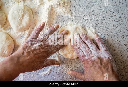 Eine Frau, die kntet und einen Kuchen macht. Hausgemachter Kuchen-Teig in den Händen der Frauen. Prozess der Tortenherstellung, Hand. Hands Pie Teig. Kocht Teig zum Backen Stockfoto
