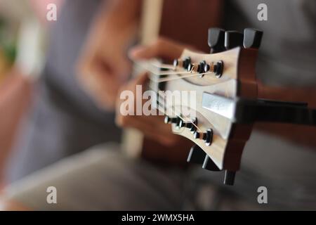 Eine Nahaufnahme fängt die emotionale Kunst der Hände ein, die eine akustische Westerngitarre spielen. Finger tanzen über das Griffbrett und überreden geschickt Melodien Stockfoto