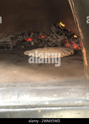 Ungekochte Pizza, die im Ofen durch Flammen gebacken wird Stockfoto