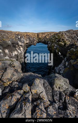 Eine Felsbrücke über dem blauen Wasser des Meeres. Island Stockfoto