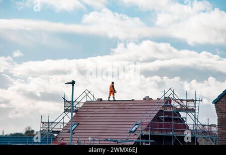 Dachdecker bei der Arbeit, Installation einer neuen Abdeckung eines Ziegeldachs. Arbeiten auf einer Gerüstplattform Stockfoto