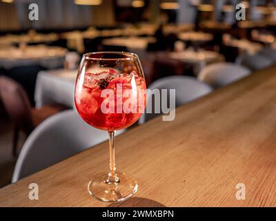 Ein Glas Orangencocktail mit aperol-Spritz. Rosafarbener Aperitif-Cocktail im Weinglas mit Sekt, Sirup und Eiswürfeln auf der Bartheke im Innenhof des Restaurants, Kopierraum Stockfoto