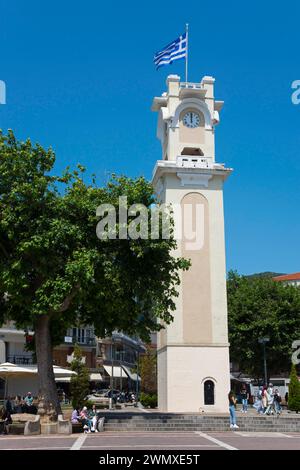 Eine Turmuhr mit der griechischen Flagge umgeben von Bäumen und Menschen in einer entspannten Atmosphäre, Xanthi, Ostmakedonien und Thrakien, Griechenland Stockfoto