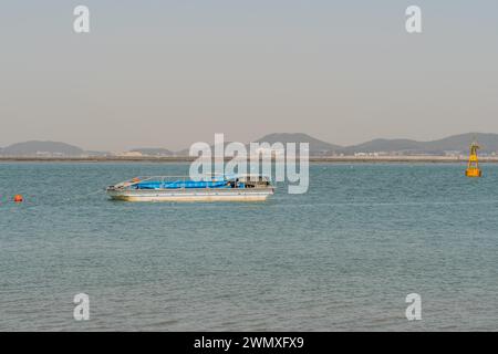 Flachbodenboot vor Anker im Hafen in der Nähe der gelben Boje in Pyeongtaek, Südkorea Stockfoto