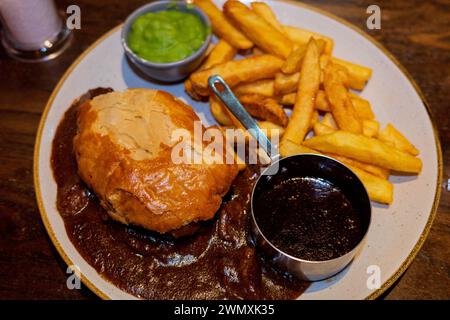 Edinburgh Steak und Ale Pie und ein Pint in einem schottischen Pub mit Pommes, Soße und matschigen Erbsen Stockfoto