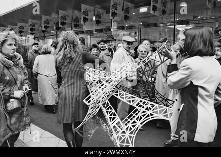 Bei der Eröffnung der Galeries Lafayette am 29. Februar tragen die Mitarbeiter ein Modell des Eiffelturms über den Bürgersteig Stockfoto