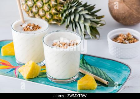 Ananas- und Kokos-Smoothies mit kohlenhydratarmem Granola auf einer farbenfrohen Platte. Stockfoto