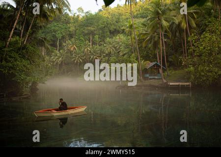 Ein Mann, der auf einem Boot am Paisu Pok Lake in Luk Panenteng, Banggai, Sulawesi, Indonesien fährt. Stockfoto