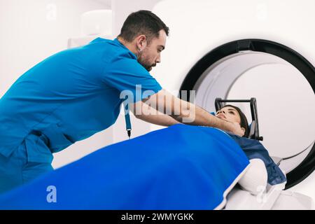 Der Techniker hilft einer Patientin vor einer Computertomographie in einem modernen klinischen Umfeld. Stockfoto