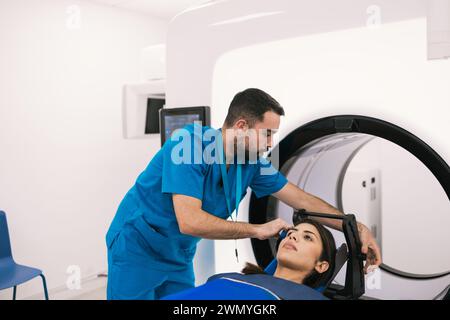 Der Techniker hilft einer Patientin vor einer Computertomographie in einem modernen klinischen Umfeld. Stockfoto