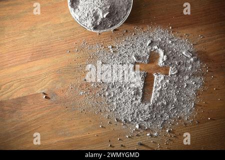 Asche in Glasbehältern und auf Holztisch mit christlichem Kreuz verstreut. Draufsicht. Stockfoto