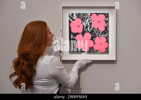 London, England, Großbritannien. Februar 2024. Der Mitarbeiter von Sotheby's hält Andy Warhol's'Flowers', die auf 500.000 bis 700.000 GBP geschätzt wurde, während der Vorschau der ersten großen Auktionen für moderne und zeitgenössische Kunst von Sotheby's im Jahr 2024. (Kreditbild: © Thomas Krych/ZUMA Press Wire) NUR REDAKTIONELLE VERWENDUNG! Nicht für kommerzielle ZWECKE! Stockfoto