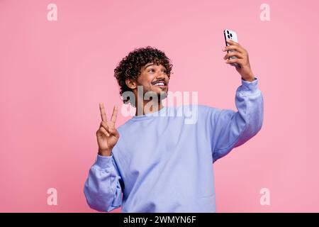 Foto-Porträt von gutaussehenden jungen Männern nehmen Selfie Fotoshow V-Zeichen gekleidet stilvolle blaue Kleidung isoliert auf rosa Hintergrund Stockfoto