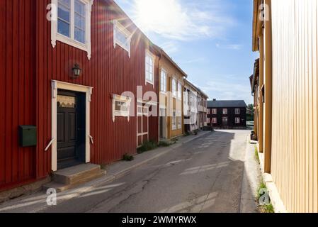 Warme Sonnenstrahlen schmücken eine gemütliche Straße in Roros und beleuchten die farbenfrohen Fassaden der historischen Holzhäuser, die die reiche Kultur der Stadt verkörpern Stockfoto