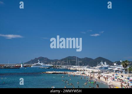 Cannes, Frankreich - August 3,2021: An einem warmen, sonnigen Tag entspannen sich die Menschenmassen am berühmten Strand Plage des Rochers in Cannes in Frankreich. Stockfoto