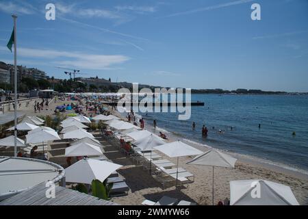 Cannes, Frankreich - August 3,2021: An einem warmen, sonnigen Tag entspannen sich die Menschenmassen am berühmten Strand Plage des Rochers in Cannes in Frankreich. Stockfoto