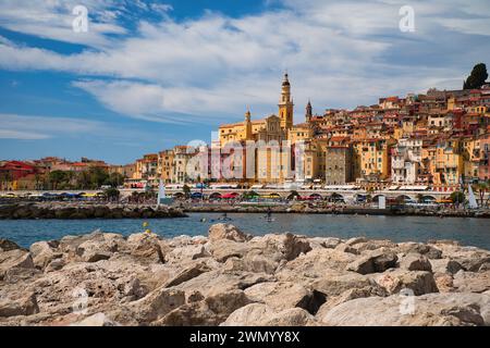 Menton, Frankreich - August 5,2021: Panoramablick auf die farbenfrohe Altstadt Menton und die Einheimischen genießen Wasseraktivitäten im Meer an einem heißen Sommertag in french R Stockfoto