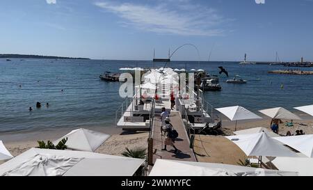 Cannes, Frankreich - August 3,2021: An einem warmen sonnigen Tag entspannen sich die Menschenmassen am berühmten Strand Plage des Rochers in Cannes. Stockfoto