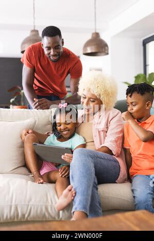 Die Familie genießt eine gute Zeit mit Technik auf einer gemütlichen Couch. Stockfoto