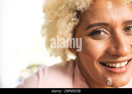 Nahaufnahme einer jungen birassischen Frau mit lockigen blonden Haaren und einem warmen Lächeln Stockfoto