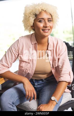 Junge Frau mit lockigen blonden Haaren lächelt warm Stockfoto