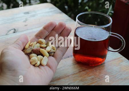 Eine Handvoll Nüsse und eine Tasse schwarzen türkischen Tee. Stockfoto