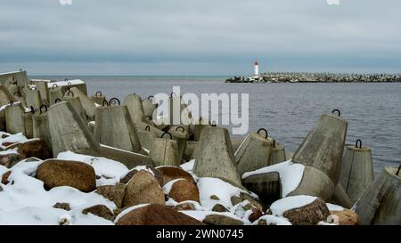 Ein ruhiges Küstenpanorama entfaltet sich vom Ventspils Northern Pier, wo die Ostsee in einer ruhigen Umarmung auf die verschneiten Küsten trifft und einlädt zum Nachdenken Stockfoto