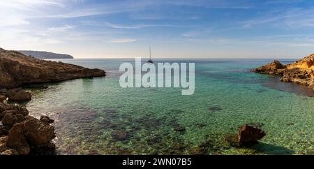Panoramablick auf eine idyllische Bucht bei es Cap Enderrocat im Süden Mallorcas mit einem Segelboot vor Anker Stockfoto