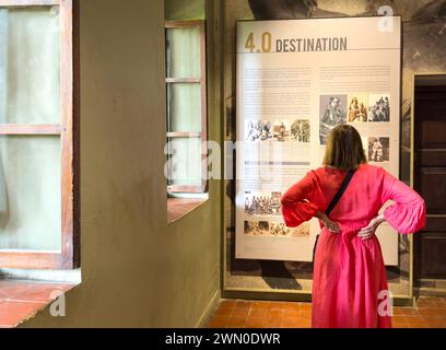 Eine westliche Touristin sieht sich eine Ausstellung in der Ostafrikanischen Sklavenhandelsausstellung in Stone Town, Sansibar, Tansania an Stockfoto