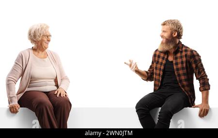 Ältere Frau, die mit einem bärtigen Kerl spricht und auf einer weißen Tafel sitzt, isoliert auf weißem Hintergrund Stockfoto