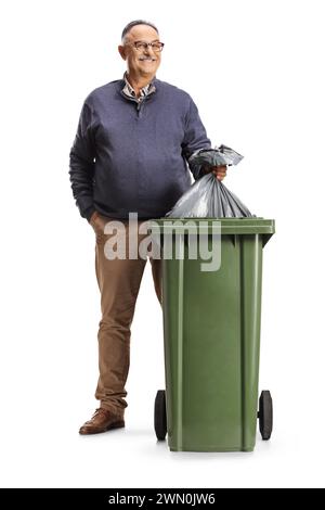 Lächelnder reifer Mann, der einen Müllsack in einen Mülleimer wirft, isoliert auf weißem Hintergrund Stockfoto