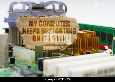 Auf der Hauptplatine des Computers befindet sich ein Karton mit der Aufschrift - mein Computer startet von selbst neu. Computerreparaturkonzept. Stockfoto