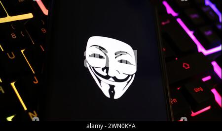 Viersen, Deutschland - 9. Januar. 2024: Smartphone-Bildschirm mit anonymen Maskensymbol auf Computertastatur als Cyber-Angriff und Hackerkonzept Stockfoto