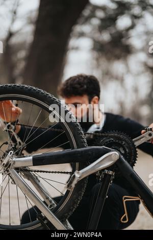 Ein fokussierter Geschäftsmann passt die Fahrradausrüstung im Freien an, stellt Multitasking und Problemlösung vor Stockfoto
