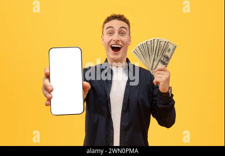 Emotionaler Kerl mit Geld Bargeld und Smartphone auf Gelb Stockfoto