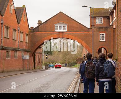 Marlborough College Gebäude privates Internat und Tagesschule mit Bogengang auf der anderen Straßenseite und Schüler spazieren entlang des Gehsteigs Wiltshire UK Stockfoto