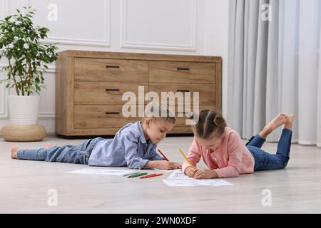 Niedliche kleine Kinder färben sich zu Hause auf warmen Böden. Heizung Stockfoto