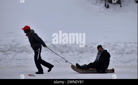 Gulmarg, Indien. Februar 2024. 28. Februar 2024, Gulmarg, Indien: Eine Person, die seinen Freund auf einem Schlitten in einem Skicamp zieht, nachdem es heftige Schneefälle gegeben hatte, die Touristen zu den Skicamps anzogen, nachdem diese Camps betroffen waren, weil es in einigen Tagen im Bezirk Gulmarg in Baramulla keinen Schnee gab. Am 28. Februar 2024 in Gulmarg, Indien (Photoby Umer Qadir/ Eyepix Group Credit: SIPA USA/Alamy Live News) Stockfoto