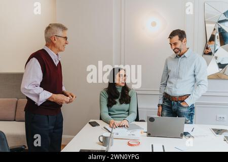 Erfahrene Geschäftspartner strahlen Professionalität und Kameradschaft aus. Laptops und Arbeitsmaterialien stehen auf dem Schreibtisch und symbolisieren produktive Geschäftstreffen. Stockfoto