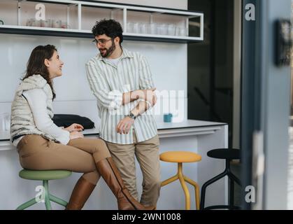 Junge Profis in einer modernen Küche, genießen Kaffee und Tee während eines fröhlichen Gesprächs. Eine entspannende Pause für Kollegen. Stockfoto