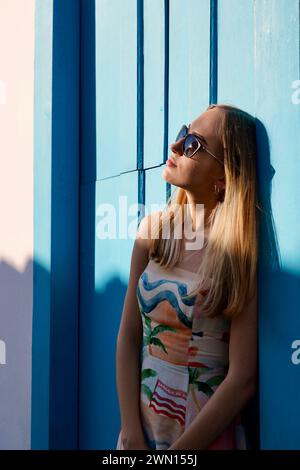 Junge Frau, die sich an die Tür lehnt und die Sonne genießt Stockfoto