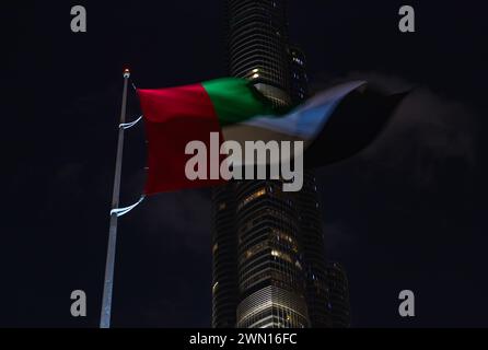 Ein Bild der VAE-Flagge, die nachts vor dem Burj Khalifa winkt. Stockfoto
