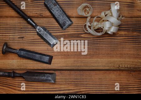 Alte Bänkmeißel und Holzrasierung auf einer verbrannten Holzoberfläche. Handwerkzeuge für die Holzbearbeitung Stockfoto